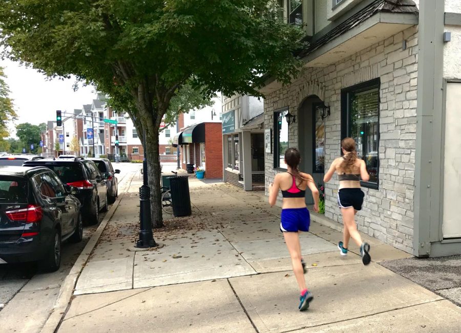 Two members of the girls cross country team run through downtown LZ. Even on runs like these, female runners say that they have to stay cautious of any threats that may come their way.