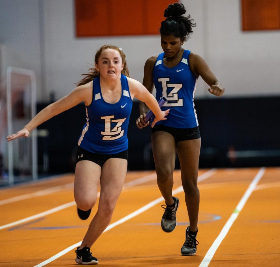 Rayna Kauffman, freshman, passes the baton to Cate Cillessen, freshman, in the Buffalo Grove Dual meet on Friday. The meet ended in a disappointing loss, but it was an improvement upon last years score in the same meet