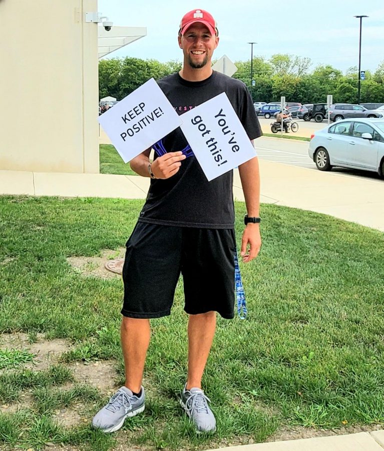 Randal Dunbar, girls cross country and boys track and field coach, poses with two signs that resemble a positive mindset. “If the players think positive, it leads to a positive experience overall, whether you’re winning or losing,” Dunbar said.
